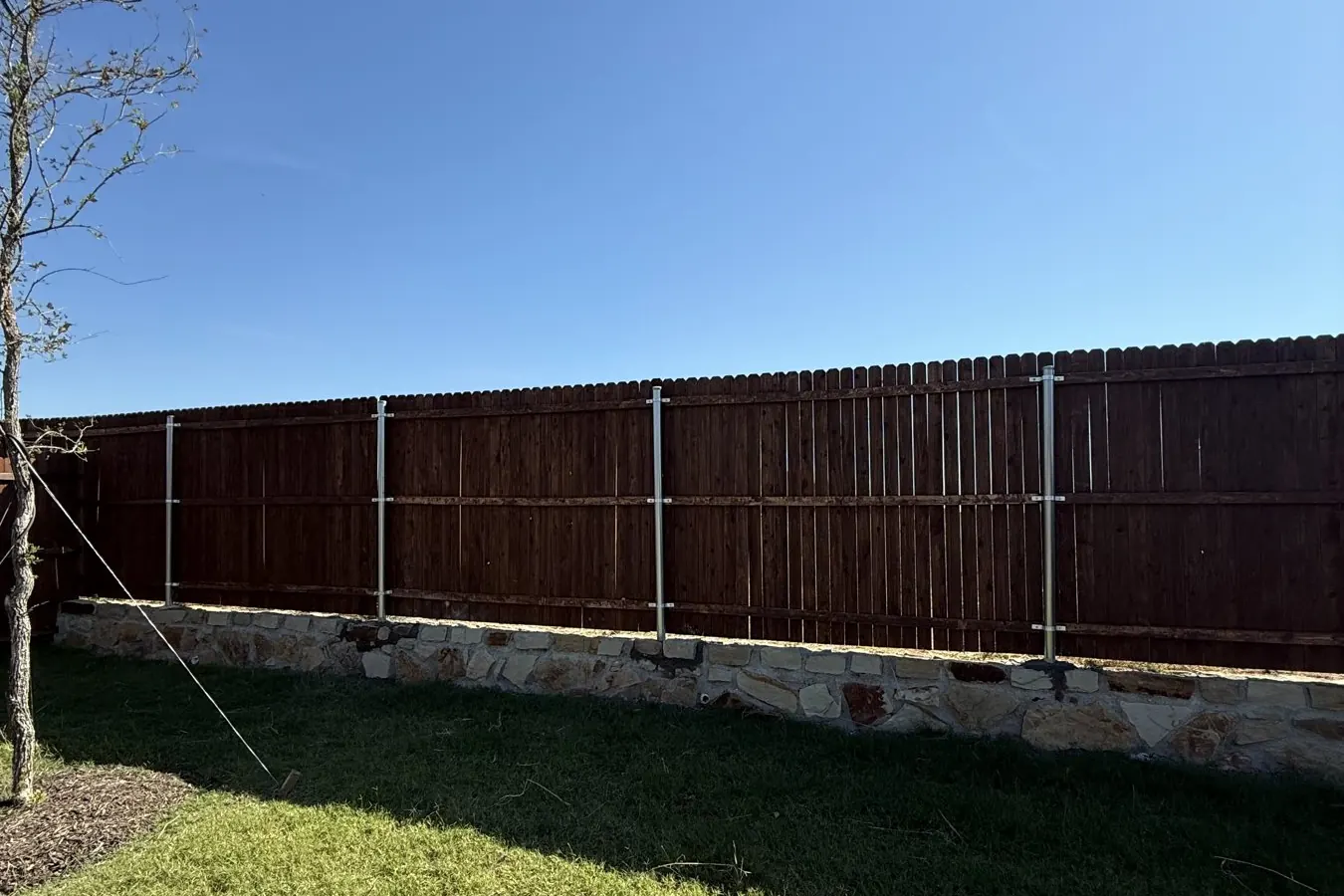 Stained cedar fence built on top of a stone retaining wall