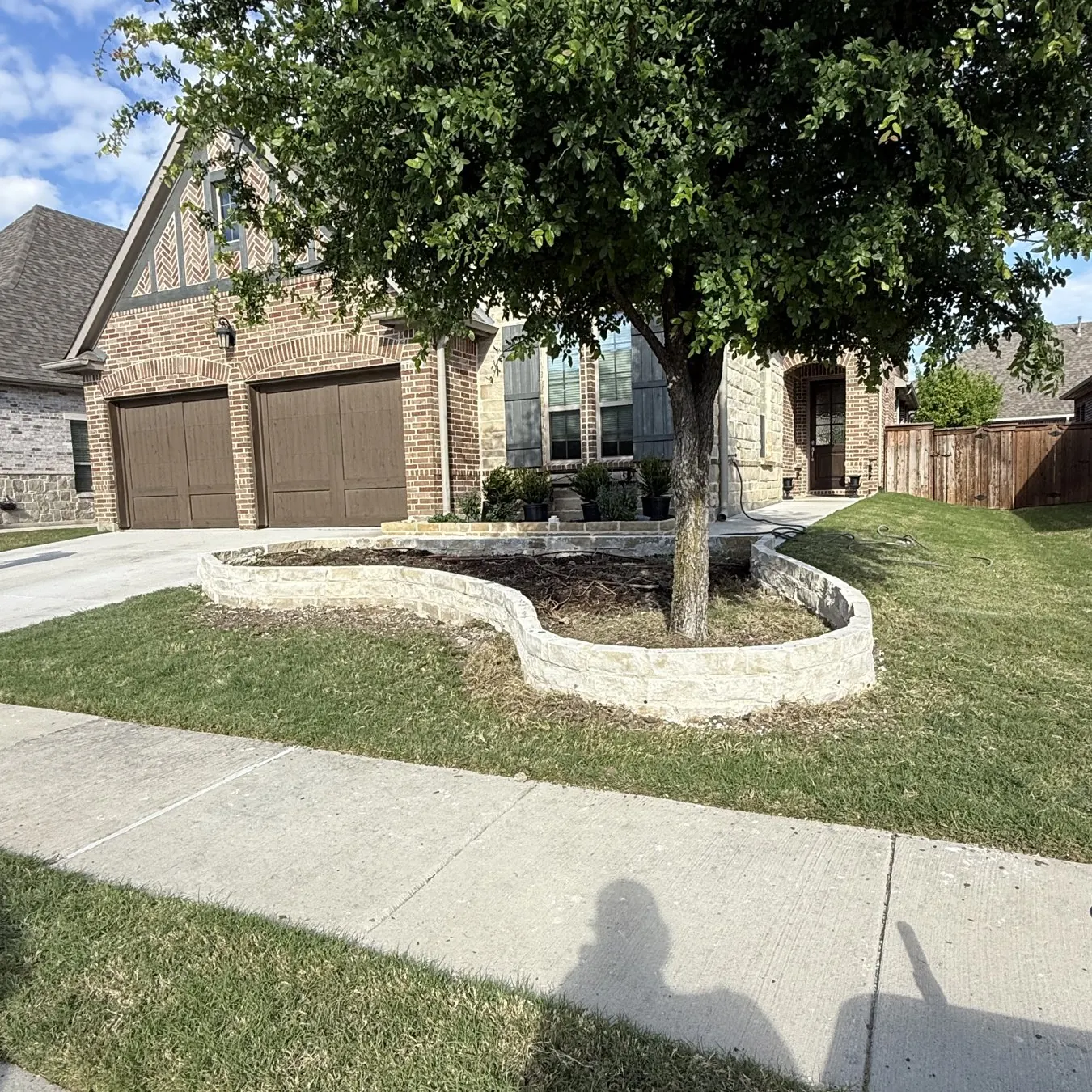 Stone flowerbed border around a front yard tree in Prosper